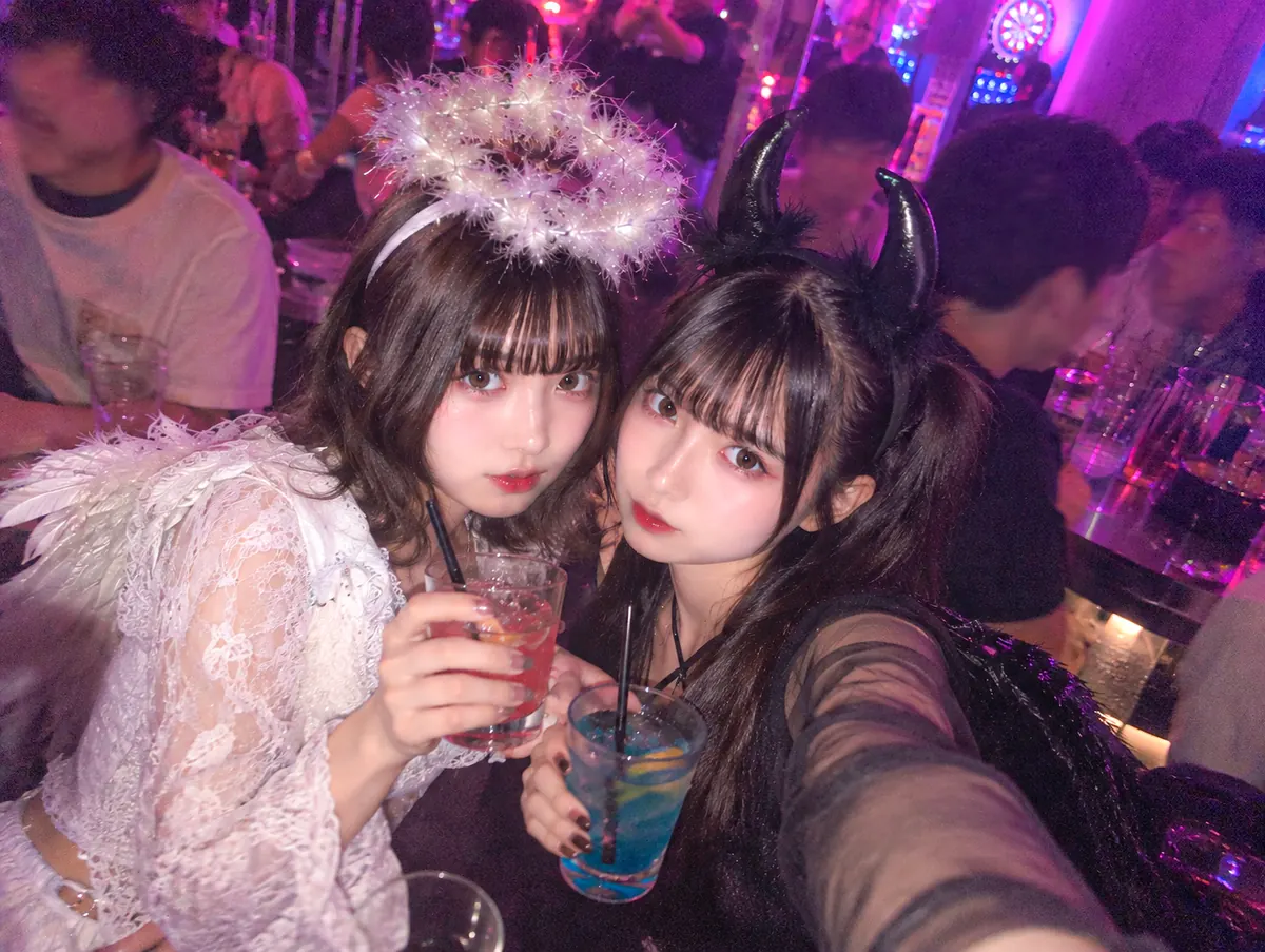 天使と悪魔の仮装をした女性2人が店内で乾杯しているイメージ